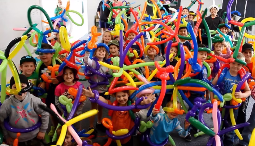 Kids showing off their finished balloon animals at library workshop